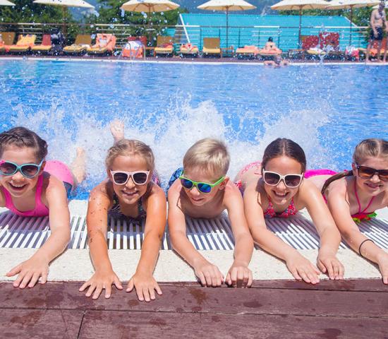 children side by side at the edge of a pool