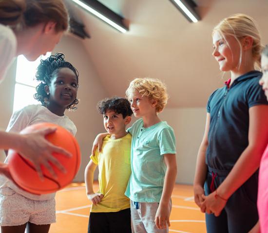 coach teaching basketball to children