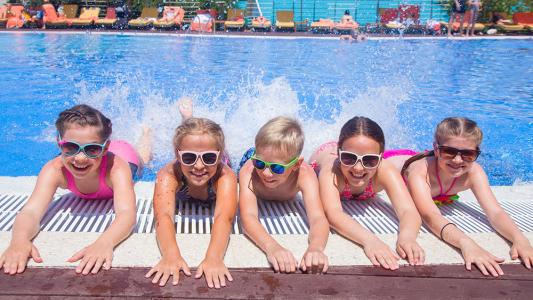 children side by side at the edge of a pool