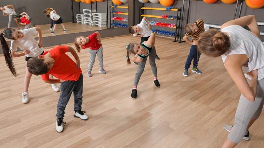 coach teaching stretching positions to children