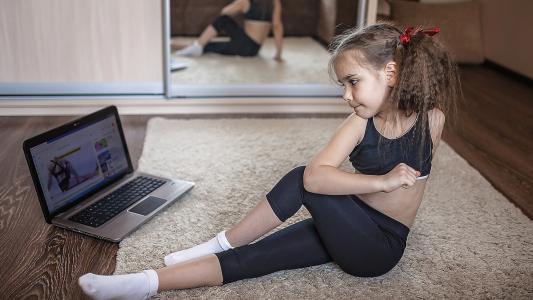 young girl in watching online video doing fitness exercises at home